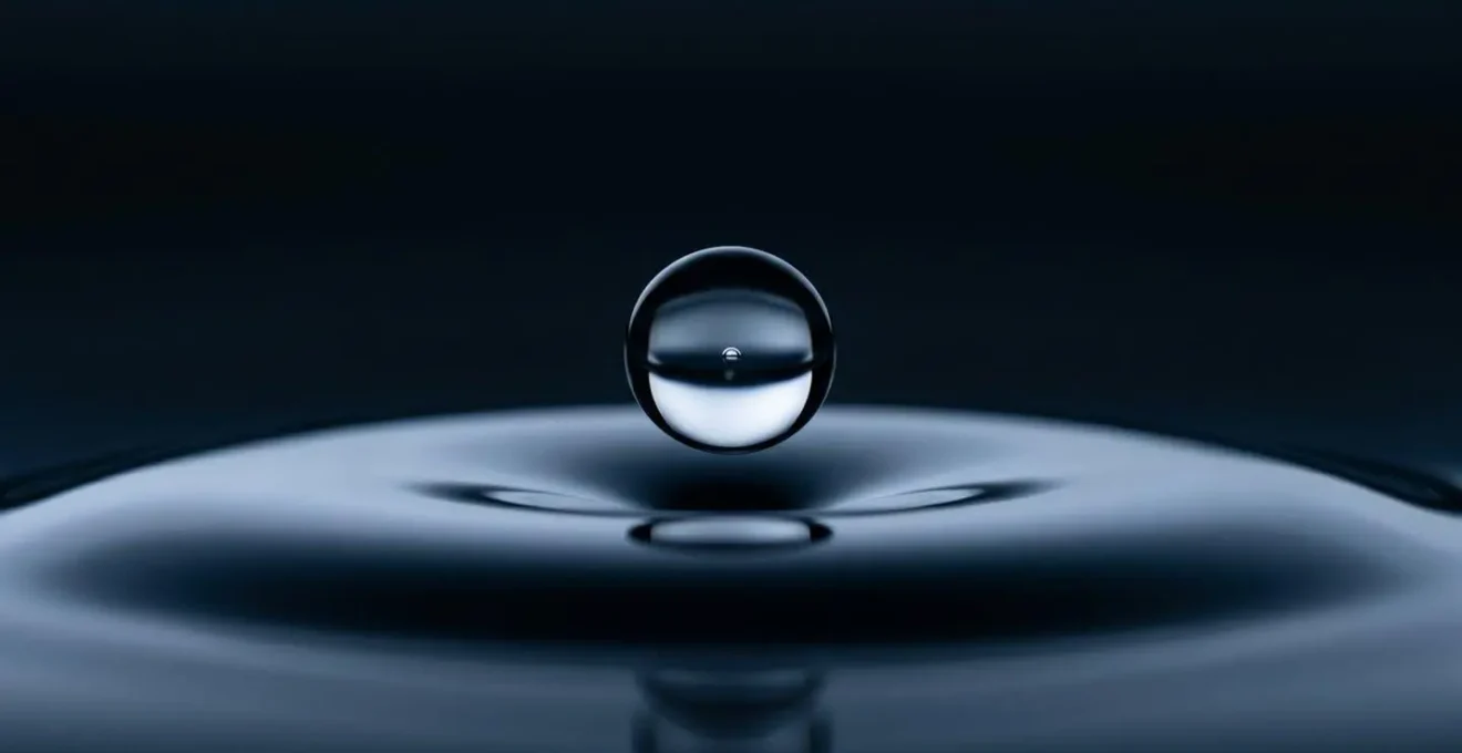 Métaphore visuelle de l'irréversibilité d'une décision financière importante, montrant une goutte d'eau sur le point de tomber dans une surface liquide calme.